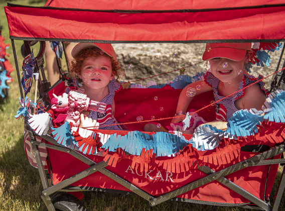 2-year-old Claire Harris, left, and her sister Emily, 5, prepare to participate  in the Hometown Parade in San Gabriel Park on Thursday, July 4, 2024.  Their grandfather, Tim Harris, founded the Hometown Parade 35 years ago.   The Georgetown Sertoma Club sponsors the 4th of July Freedom Festival each year in San Gabriel Park.  Photo by Andy Sharp.