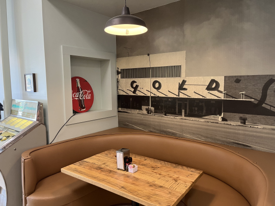 The front booth at Gold Burger Diner has a black-and-white photo of the old Gold’s Department Store on the wall. A jukebox is positioned against the wall.