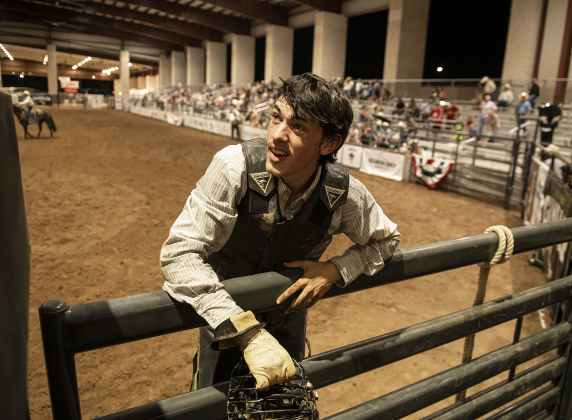 Dusty Rhodes, a Bull Riding competitor from Sanger, Texas holds onto the arena fencing after being thrown from the bull he was riding.