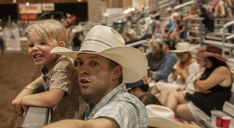 -year-old Landon Smith and his dad Corey Smith watch the action at the 74th Annual Taylor Rodeo.