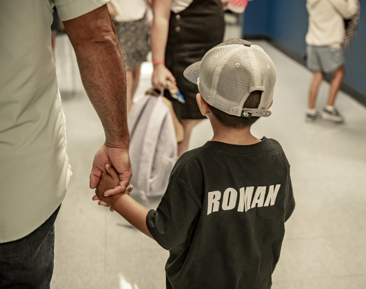 Dad Rigo Garcia holds the hand of his son Roman, 4, as they make their way through a hallway to Roman's Pre-K classroom  at Cooper Elementary on Thursday morning, August 15, 2024,  the first day of school.   Cooper Elementary has 572 students enrolled this year.    Photo by Andy Sharp.