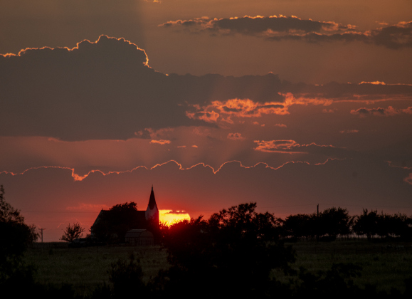 The sun begins to go down over Christ Lutheran Church  on Wednesday, August 21, 2024.  The church is along F.M. 112, the photo taken from County Road 450.    Photo by Andy Sharp.