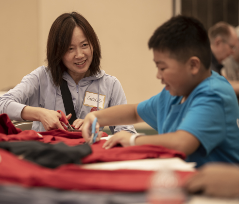 Grace Lei, left, and her son Kevin, 12, help  create bags out of donated t-shirts during a 9/11 National Day of Service event held at Georgetown's Christ Lutheran Church on Saturday, September 7, 2024.  Volunteers from churches, synagogues and mosques, including some who just wanted to contribute helped repurpose t-shirts to be used as bags at The Caring Place, Helping Hands of Georgetown and the Carver Center for Families.   Photo by Andy Sharp.