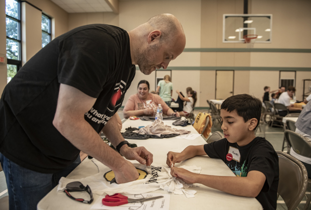 Tom Minerd, left, with the Church of Jesus Christ of Latter Day Saints in Round Rock, helps 8-year-old Haseeb Sheikh, with the Ahmadiyya Muslim Community, as they work to  create bags out of donated t-shirts during a 9/11 National Day of Service event held at Georgetown's Christ Lutheran Church on Saturday, September 7, 2024.  Volunteers from churches, synagogues and mosques, including some who just wanted to contribute helped repurpose t-shirts to be used as bags at The Caring Place, Helping Hands of Georg