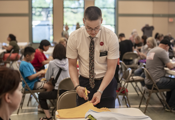 Elder Oakley Sorenson, with the Church of Jesus Christ of Latter Day Saints (in Georgetown) helps  create bags out of donated t-shirts during a 9/11 National Day of Service event held at Georgetown's Christ Lutheran Church on Saturday, September 7, 2024.  Volunteers from churches, synagogues and mosques, including some who just wanted to contribute helped repurpose t-shirts to be used as bags at The Caring Place, Helping Hands of Georgetown and the Carver Center for Families.   Photo by Andy Sharp.