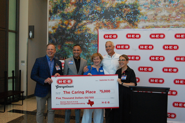 Representatives from H-E-B, The Caring Place and Mayor Josh Schroeder pose with a donation for $5,000.