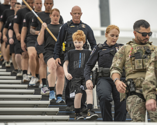 10-year-old T.C. Grasse is flanked by his mom and dad, Georgetown Police Department Commander Erik Grasse (behind T.C.) and Police Department Commander Renee Koog (in front of T.C.) as they take part in the Memorial Stair Climb at Birkelbach Field on Wednesday, September 11, 2024, the 23rd anniversary of the attacks on United States soil in New York, Pennsylvania and Washington, D.C.  T.C. did the entire walk with his parents.  The Memorial Stair Climb began here in 2011.  Photo by Andy Sharp.