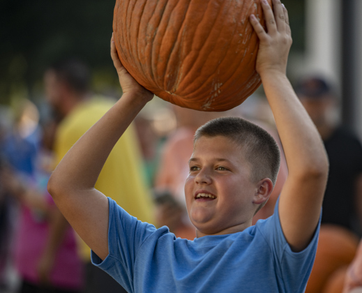 11-year-old Brendan Meredith helps unload pumpkins at First United Methodist Church on Wednesday, October 9, 2024.  2,880 large pumpkins, plus many smaller versions were unloaded at the church.   The pumpkins were grown in New Mexico.   A second, but smaller batch of pumpkins will arrive from there on October 19th.   Sales continue through 5p.m. on October 31st.    Photo by Andy Sharp.