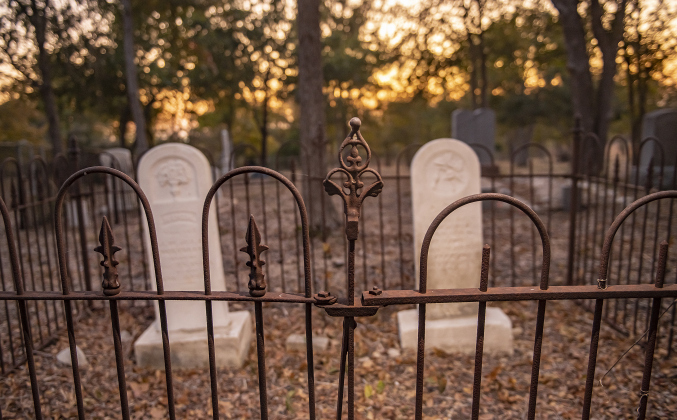 Ornamental ironworks frame gravesites at the circa 1851 McFadin Cemetery on Tuesday, October 8, 2024. Joe Plunkett and his group, Williamson County Cemetery Restoration Volunteers,  led the effort to restore this cemetery near the San Gabriel River in recent years.     Photo by Andy Sharp.