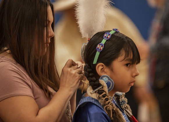 Jacqueline Abrego prepares her daughter Elaina, 9, for a dance during  the 2024 Georgetown Powwow, held Saturday, September 28, 2024 at the Boys and Girls Club of Georgetown.  Elaina's Lipan Apache name is "Little Dove," says her father, Nathan Abrego.  Sponsored by GTX Connect, this is Georgetown's first Powwow since the event  was last held at Southwestern University in 2019.  Photo by Andy Sharp.
