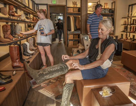 Denise Arndt tries on a pair of boots during Tecovas Grand Opening  on Friday, September 27, 2024.  The store is along Main Street, in the area under the Williamson County Sun offices.   Photo by Andy Sharp.