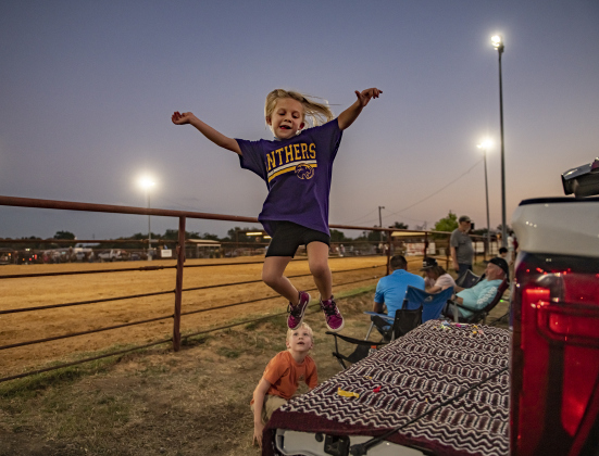 6-year-old Annie Hale, joined by her cousin Owen Walther, 7 (at bottom of photo), had fun jumping off the back of a family pickup truck near the conclusion of  the 31st Annual Clayman Rodeo on Saturday, October 5, 2024.  Owen's sister Emory Walther competed in Barrel Racing.   Held at Windsong Farm, the rodeo was founded by Kelly and Jim Bob Clayman.    Photo by Andy Sharp.