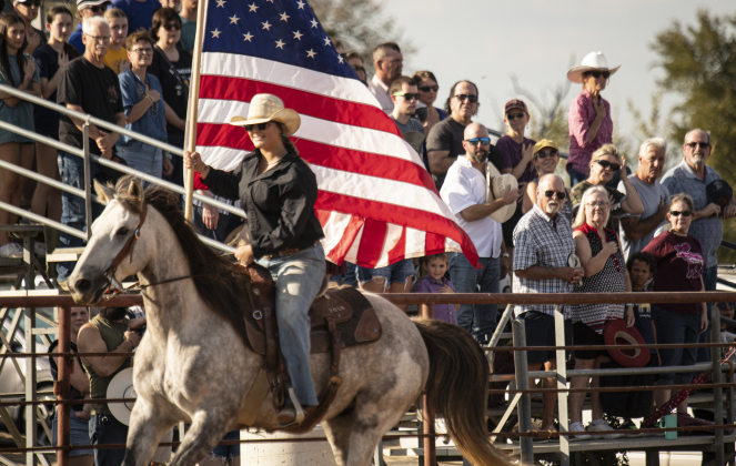 Jenna Anderson carries the American flag through the arena at the start of  the 31st Annual Clayman Rodeo on Saturday, October 5, 2024.  Held at Windsong Farm, the rodeo was founded by Kelly and Jim Bob Clayman.    Photo by Andy Sharp.