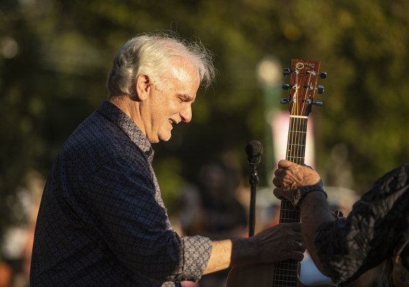 Ken Covington accepts a guitar from friend Bob Case as he prepares to perform with Case during a First Friday Concert held at Founders Park on Friday, October 4, 2024.  Covington, founder of Kenz Guitars,  suffered a stroke in September 2023.  He's been on the mend for the past year.  He was honored with a proclamation presented by Georgetown Mayor Josh Schroeder.   Photo by Andy Sharp.