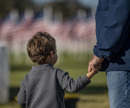 3-year-old Claude Knapp holds the hand of his great-grandfather Dennis Brown as they visit the Field of Honor  on Saturday, November 9, 2024, its official opening day.   Sponsored by the Rotary Club of Georgetown, the Field of Honor includes 2,000 American flags covering ten acres in San Gabriel Park.  With events throughout the week, the flags will fly here until November 17th.   Photo by Andy Sharp.