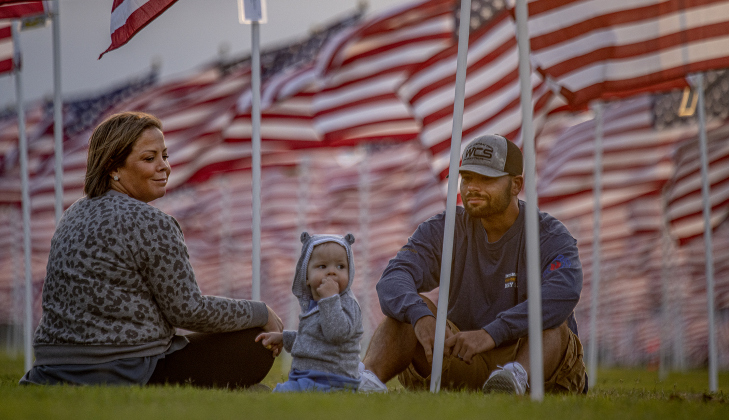 Morgan and Stephen Coop and their son Spencer, who will be one-year-old on December 1st, enjoy a relaxing evening under American flags at the Georgetown Field of Honor on  Friday, November 8, 2024.  Sponsored by the Rotary Club of Georgetown, the Field of Honor includes 2,000 American flags covering ten acres in San Gabriel Park.  With events throughout the week, the flags will fly here until November 17th.   Photo by Andy Sharp. 