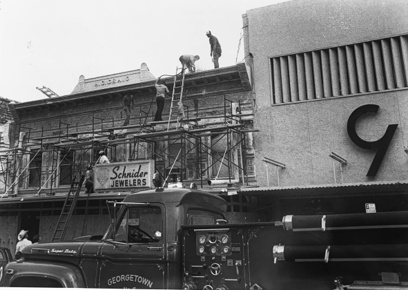 Construction workers fix the facade of a jewelry store next to Gold’s department store as part of the Main Street Program. (Sun Archive)