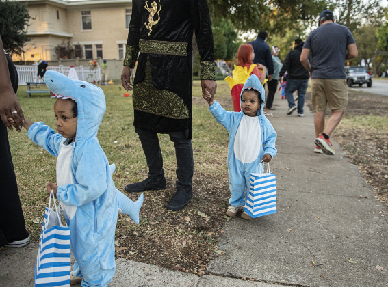 Lila Cash, 2, front, and her  identical twin Kira, dressed as baby sharks, are accompanied by their mom and dad, Jessica and Caleb Cash during  Halloween night along Main Street  on Thursday, October 31, 2024.   Photo by Andy Sharp.