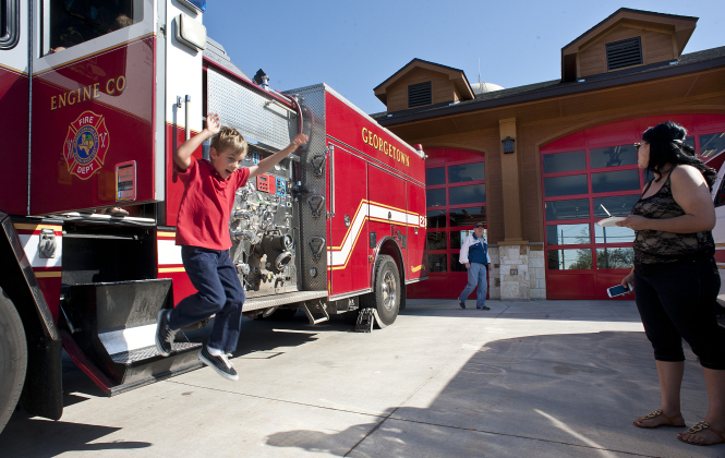 7-year-old Max Acker makes a big leap from a fire engine he looked over at the dedication ceremony of the Georgetown Fire Department's new Station 2 on Saturday, March 16, 2013.