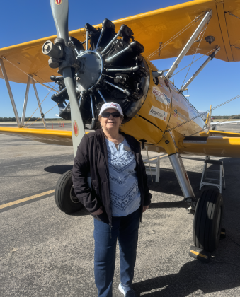 The Oaks resident Maggie Cardona poses by the WWII era plane. (Photo courtesy Sport Clips)