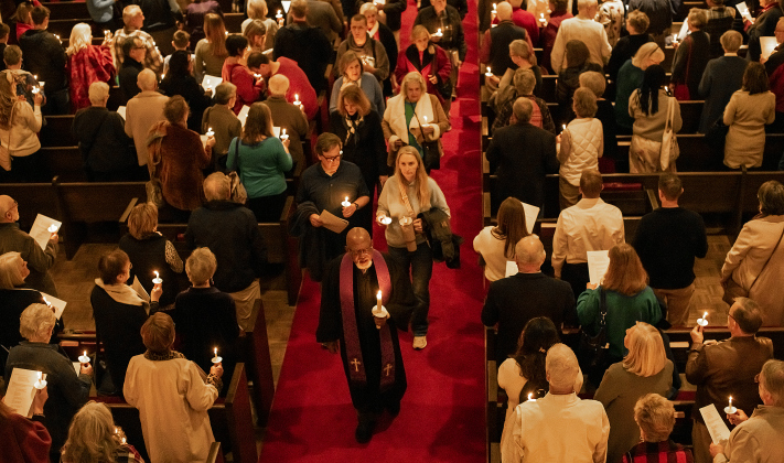 With candles in hand, attendees, led by Rev. Dr. Ronald L. Swain,  file out of  Lois Perkins Chapel for the first of two candlelight services at Southwestern University  on Thursday, December 5, 2024.  Dr. Swain is Southwestern University Chaplain and Director of Spiritual Life.  The annual Service of Lessons and Carols began in 1915, then called the Christmas Carol Service.   Photo by Andy Sharp.