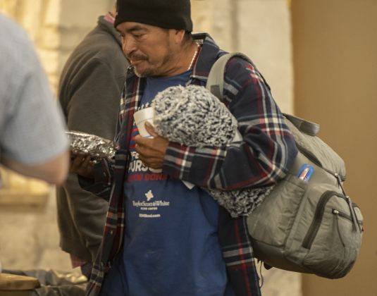 Edgar Ramirez leaves the community center with his belongings and a wrapped to-go plate of food during the Community Thanksgiving.