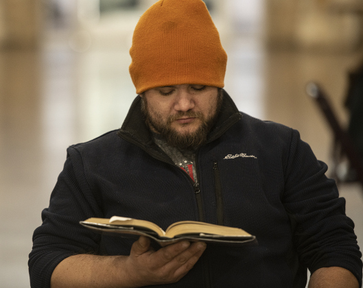 Ryan Walters, an avid reader, brought a book to read before meals were served  during the Community Thanksgiving, held Thursday, November 28, 2024 at the San Gabriel Community Center in San Gabriel Park.