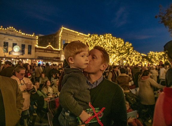 Bobby Cooley and his son Rowen, 3, enjoy a quiet moment at  the annual Lighting of the Square in downtown Georgetown on  Friday, November 29, 2024. The streets and courthouse lawn were jammed with thousands of attendees on a cool autumn evening.    Photo by Andy Sharp.