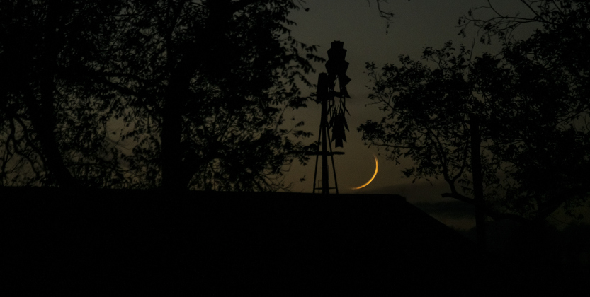 A Waxing Crescent moon, at just 3.4% visibility, is a warm presence over County Road 483 north of Coupland on Monday evening, December 2, 2024.     Photo by Andy Sharp. 