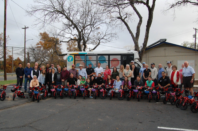 Members from YMCA of Georgetown, SportClips, Opportunities for Williamson and Burnet Counties and Grand Endeavor homes gather around the bikes for the kids.