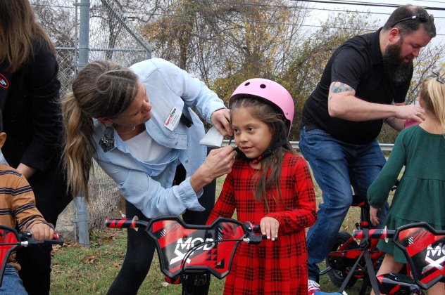 Emily Baker, left, helps Ariyah Robles adjust the strap on her helmet.