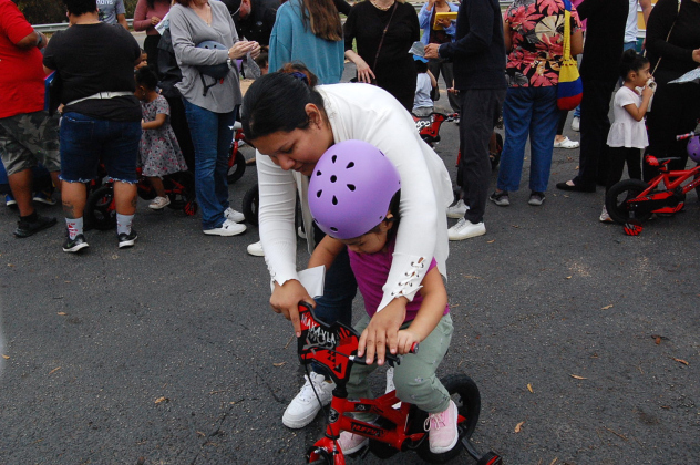 Mom Adileni Rodriguez helps her daughter Makayla get started on her bicycle.