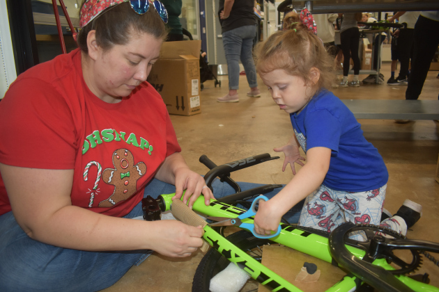 Little Remmington Heppner and her mom, Emma, get started on a bike assembly. “We’re helping people that doesn’t have bikes,” Remmington said.