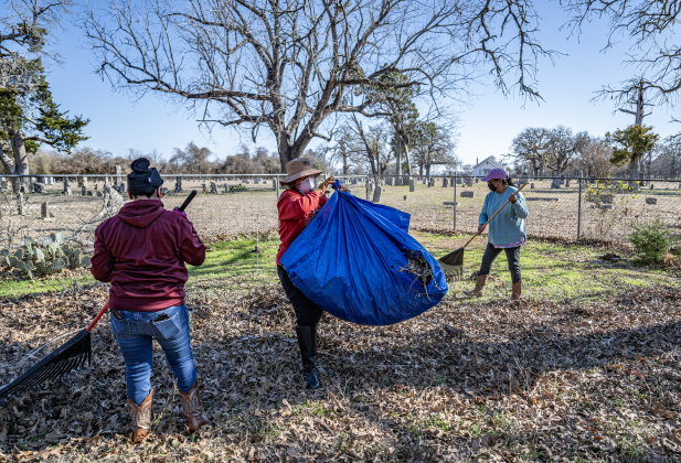 Victoria Arellano, left, her aunt Teresa Shipley, center, and Delores Moreno, Teresa’s first cousin, back right, gather leaves in an unnamed cemetery adjacent the Lawrence Chapel Cemetery on Saturday, January 18, 2025.  Lawrence Chapel Cemetery is seen behind them.