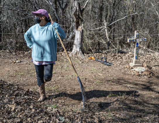 Delores Moreno pauses from her cleanup work in an unnamed cemetery adjacent to  the Lawrence Chapel Cemetery on Saturday, January 18, 2025. The cross at right is the burial site for Jose Garcia, her great-great-great grandfather, born in the mid-1800s, living until the early-1900s.