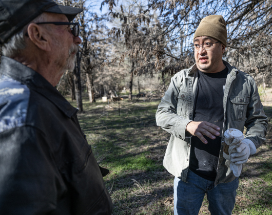 Mike Hopf, left, one of eight area trustees overseeing the site, visits with Eric Arellano  in an unnamed cemetery adjacent the Lawrence Chapel Cemetery on Saturday, January 18, 2025.