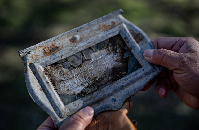 Teresa Shipley, doing cleanup work  in an unnamed cemetery adjacent the Lawrence Chapel Cemetery on Saturday, January 18, 2025, looks at a barely legible grave marker found in the dirt.
