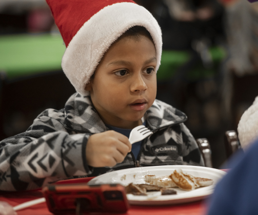 7-year-old Kaiden Lyons enjoys his pancakes and sausage during Breakfast With Santa, held Saturday, December 21, 2024 at the San Gabriel Community Center.  The event, coordinated by the Georgetown Fire Department and the Rotary Club of Sun City, served up pancakes, sausage, juice and coffee to attendees.  Santa Claus was there throughout the morning to visit the kids and their families.    Photo by Andy Sharp.