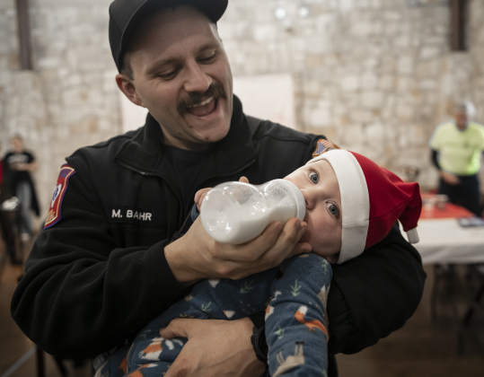 Georgetown Fire Department member Matt Bahr gives his 7-month-old son Landon a bit of formula before Landon visited with Santa Claus for the first time during  Breakfast With Santa, held Saturday, December 21, 2024 at the San Gabriel Community Center.  The event, coordinated by the Georgetown Fire Department and the Rotary Club of Sun City, served up pancakes, sausage, juice and coffee too attendees.  Santa Claus was there throughout the morning to visit the kids and their families.    Photo by Andy Sharp.