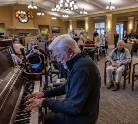 Duane Smith, left, who traveled from Portland, Oregon,  plays piano and sings for his uncle, Al Blaschke (seated at back right)  who celebrated his 108th birthday with a party  at The Wesleyan Assisted Living on Saturday, January 4, 2025.