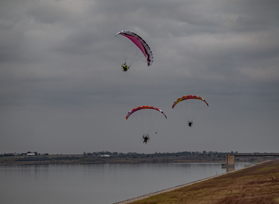 Paramotor enthusiasts fly over Granger Lake  on Friday, January 3, 2025.  Several paramotor pilots made their way to Granger Lake before returning to their starting point near Taylor Regional Park.   The Friday evening weather was cloudy, but warm, good conditions for paramotor flights.  The temperatures in the area are expected to plummet by Sunday evening.   Photo by Andy Sharp.
