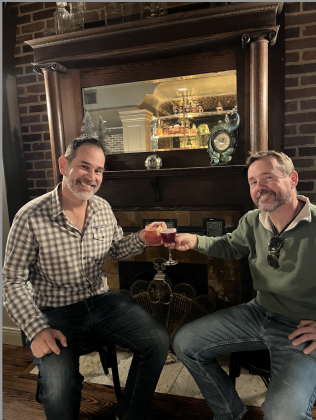 Owner Kevin Cummins, right, and his business partner Thomas Zavaleta cheers in front of the mock fireplace. Photo by Abbey Archer