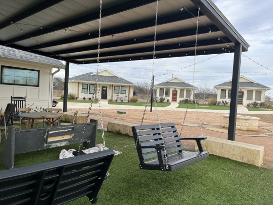 One-bedroom homes at the Tiny Home Village surround a club house that has a kitchen, dining and living room, and a porch with swings. Every evening, residents of the tiny homes eat dinner and play games in the club house. There is a manager that lives in a three bedroom home in the village who cares for the residents.