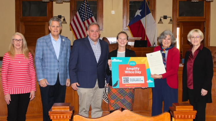 Piper Stege Nelson, executive director of I Live Here I Give Here, center, holds a sign promoting Amplify Wilco next to the county commissioners, February 25. Photo courtesy of Williamson County.
