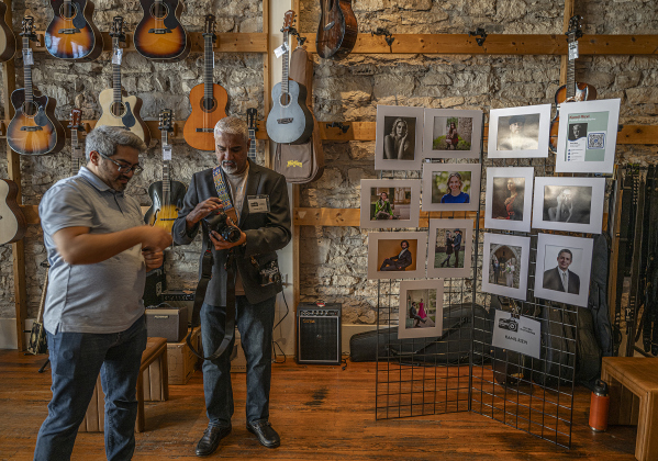 Festival attendee Gall Levi, left, spends time with featured photograph Kamil Rizvi at Six Strings Guitar and Lounge.