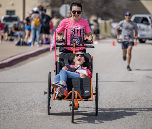 Ainsley’s Angels team member Noelle Swartz is assisted by Taylor Gadds as they near the 5K race finish line  during the 13th Annual Chase the Chief, held Sunday, March 2, 2025 at East View High School.   2,000 people were registered for the one-mile fun run and 5K event.   Proceeds from the races support physical education programs in Georgetown.   Photo by Andy Sharp.