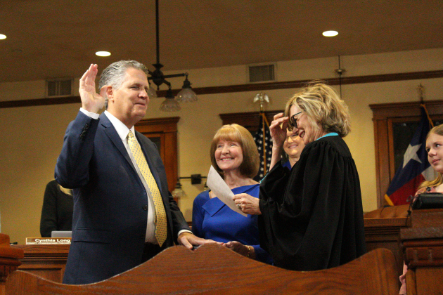 Bill Gravell, left, is sworn in by Judge Besty Lambeth, right, as the Region Six advocate for Small Businesses in America in the Office of Advocacy, March 11. Jill Gravell, center, holds a Bible as Mr. Gravell recites the oath. Photo by Nalani Nuylan.