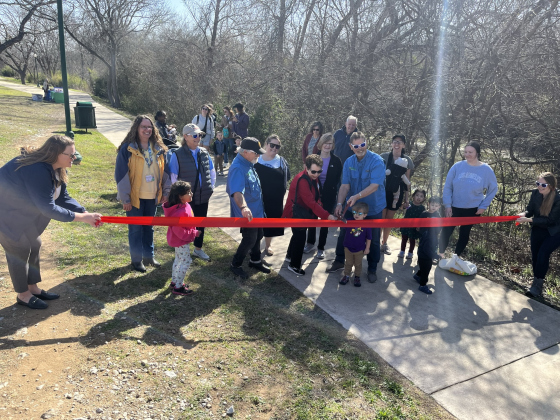 Parks and Recreation and library staff, members from Friends of the Georgetown Library, and families help cut the ribbon for the storywalk at San Gabriel Park. 