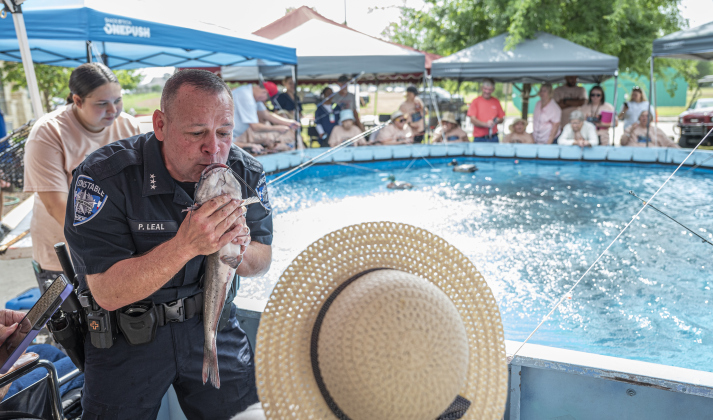 Precinct 4 Constable Paul Leal, one of the volunteers, with other members of his department, tries to coax 99-year-old Ruby Fisher to kiss the catfish she caught (she decided against it)  during the 22nd Annual Fishing Tournament held at Taylor’s SPJST Senior Living  on Thursday, April 24.