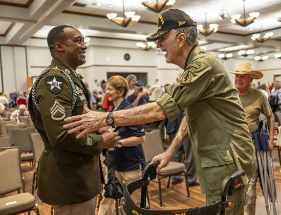 Army Sgt. Craig Roy, left, a member of the 3rd Cavalry Regiment Rifle Honor Guard, meets former Army Special Forces member Robert “Too Tall” Simmons, right, who will be 92 in June, at  the conclusion of the Memorial Day ceremony in Sun City on Monday, May 26, 2025.  Approximately 600 were in attendance.  Rain chances moved the event indoors.   Photo by Andy Sharp.